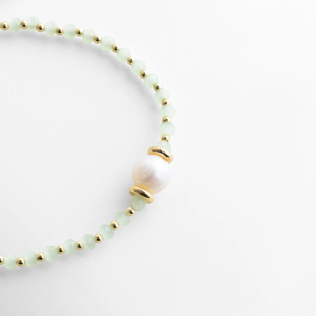 Detalle de pulsera con perla de agua dulce y separadores dorados, Close up de pulsera con perla central y cuentas de cristal delicadas, Pulsera con perla natural y acabado fino, estilo elegante moderno, Detalle de perla de agua dulce en pulsera ajustable con cordón, Pulsera fina con perla central y diseño minimalista sofisticado
