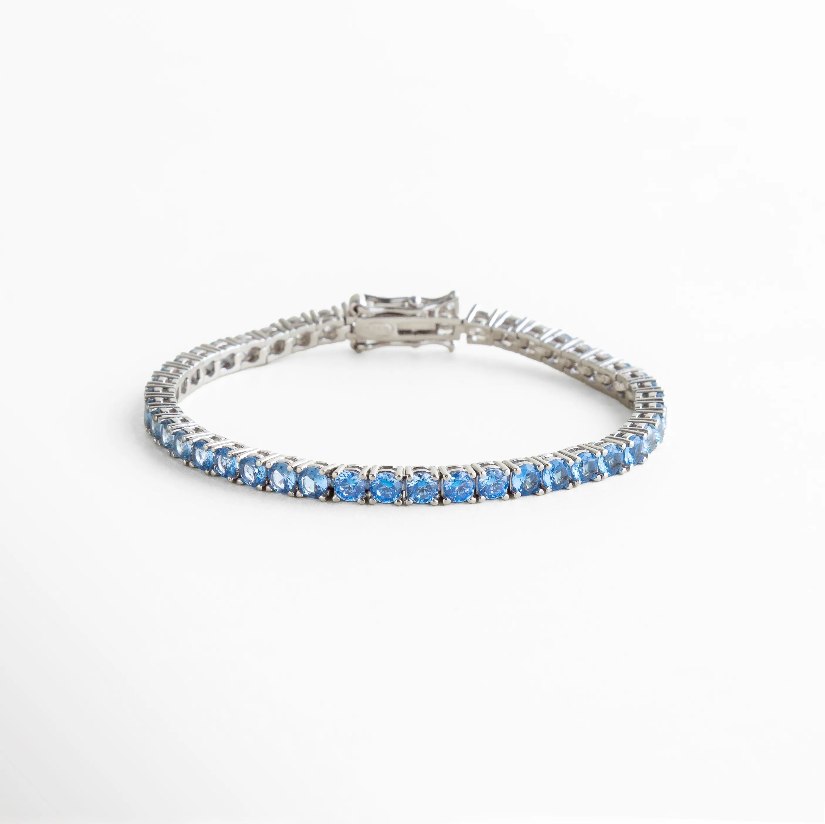 pulsera tennis azul, pulsera plateada con piedras azules, joyería elegante con color, pulsera femenina sofisticada, pulsera con brillo continuo, accesorios azules mujer, joyería luminosa moderna, pulsera delicada azul