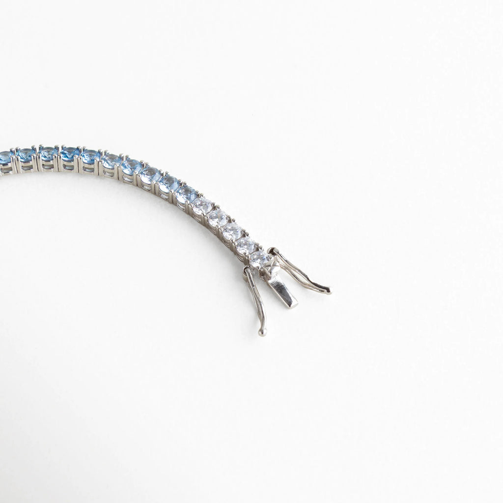 detalle pulsera tennis, broche pulsera plateada, joyería plateada fina, pulsera elegante con cierre, accesorios sofisticados mujer, pulsera clásica moderna, joyería femenina luminosa, pulsera de diseño elegante