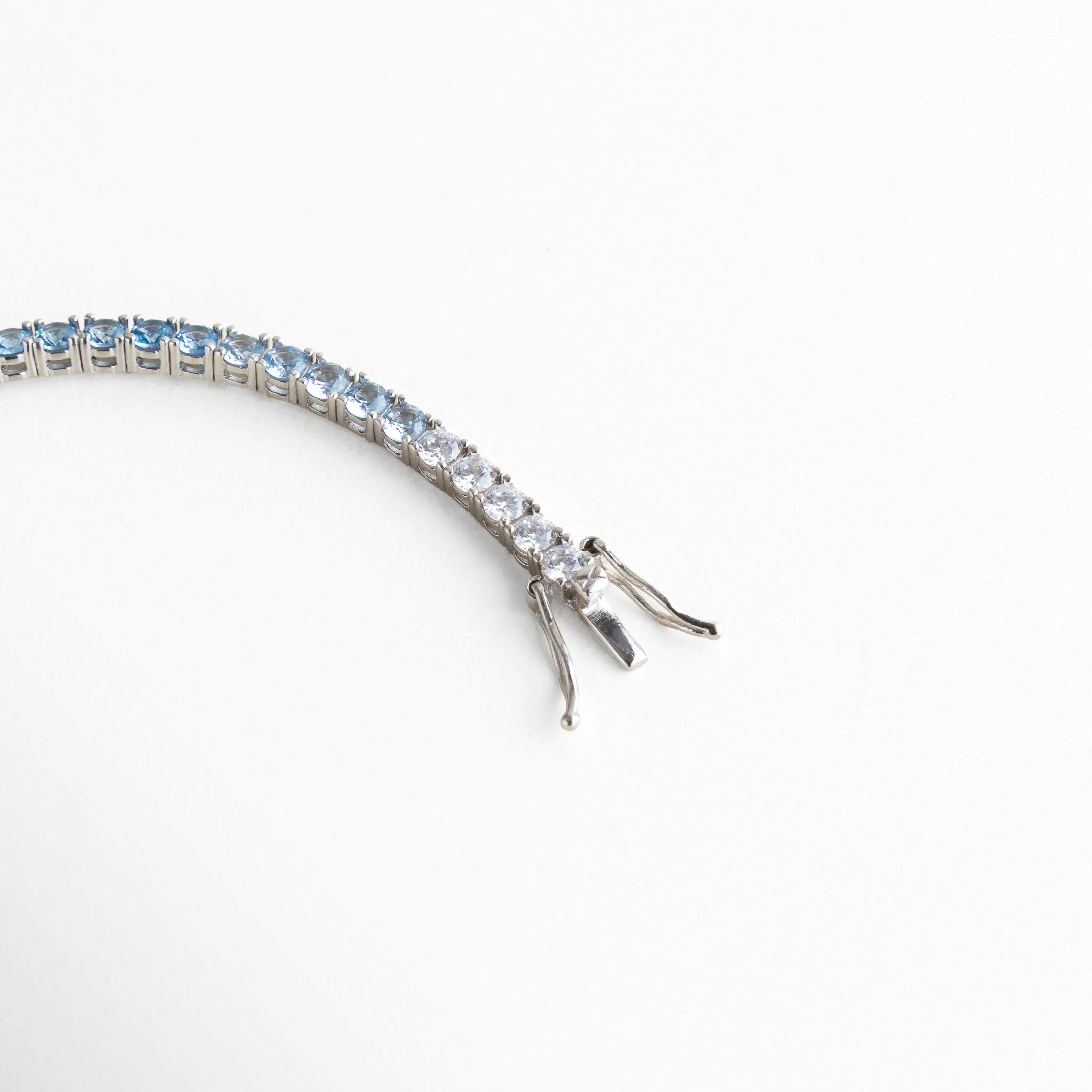 detalle pulsera tennis, broche pulsera plateada, joyería plateada fina, pulsera elegante con cierre, accesorios sofisticados mujer, pulsera clásica moderna, joyería femenina luminosa, pulsera de diseño elegante