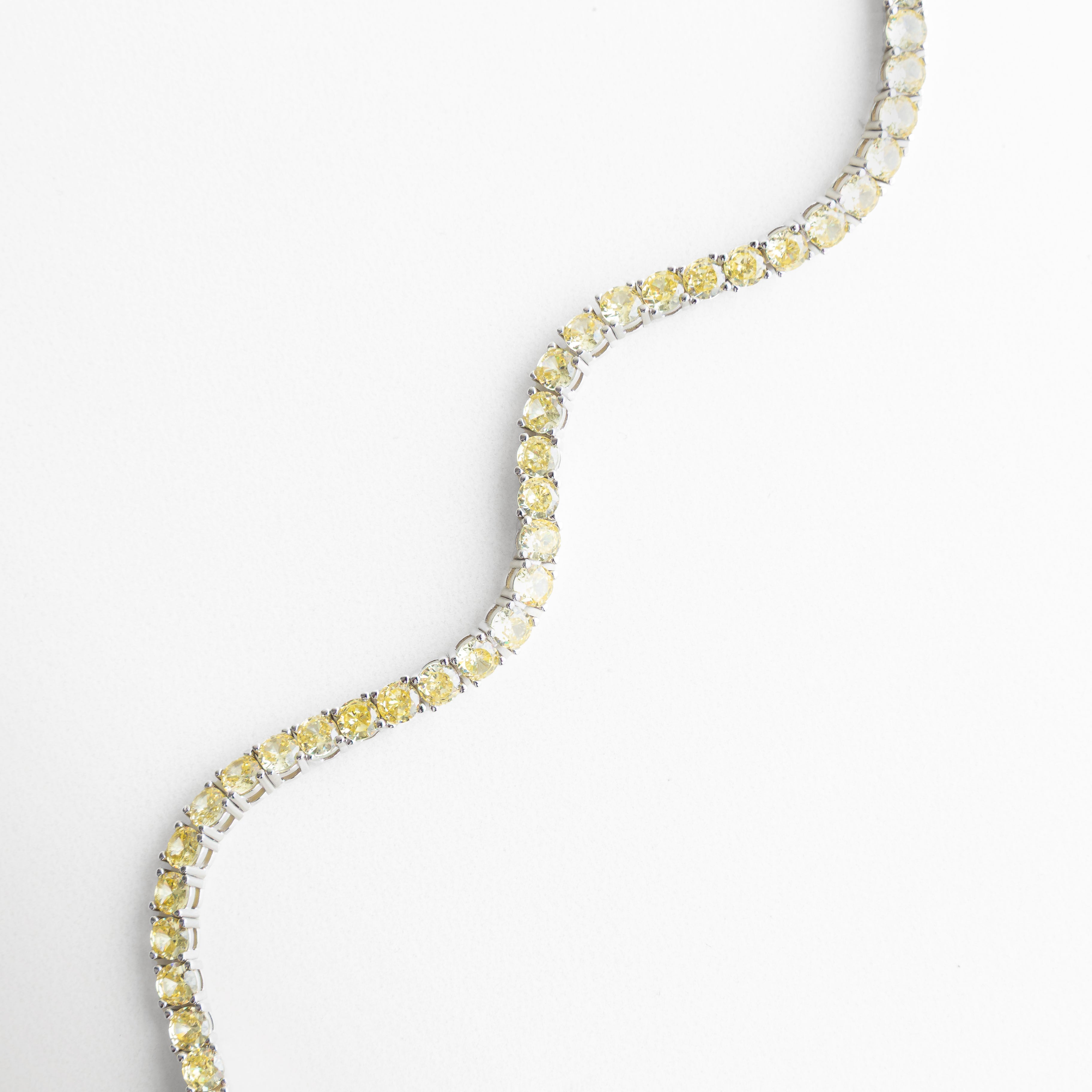 Pulsera tennis flexible con zirconias brillantes, Detalle diagonal de pulsera de joyería elegante, Pulsera de zirconias vista diagonal sobre fondo blanco, Diseño continuo de pulsera tipo tennis, Pulsera fina con engaste uniforme de zirconias