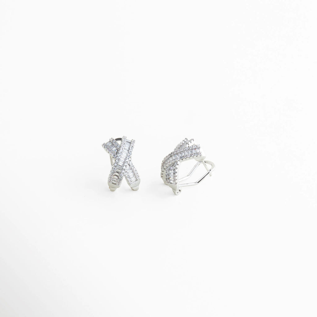 aretes plateados cruzados vistos en ángulo, detalle de zirconias en aretes tipo X, aretes elegantes con textura y brillo, diseño cruzado moderno en aretes pequeños, aretes plateados con acabado pulido, joyería contemporánea aretes stud con piedras