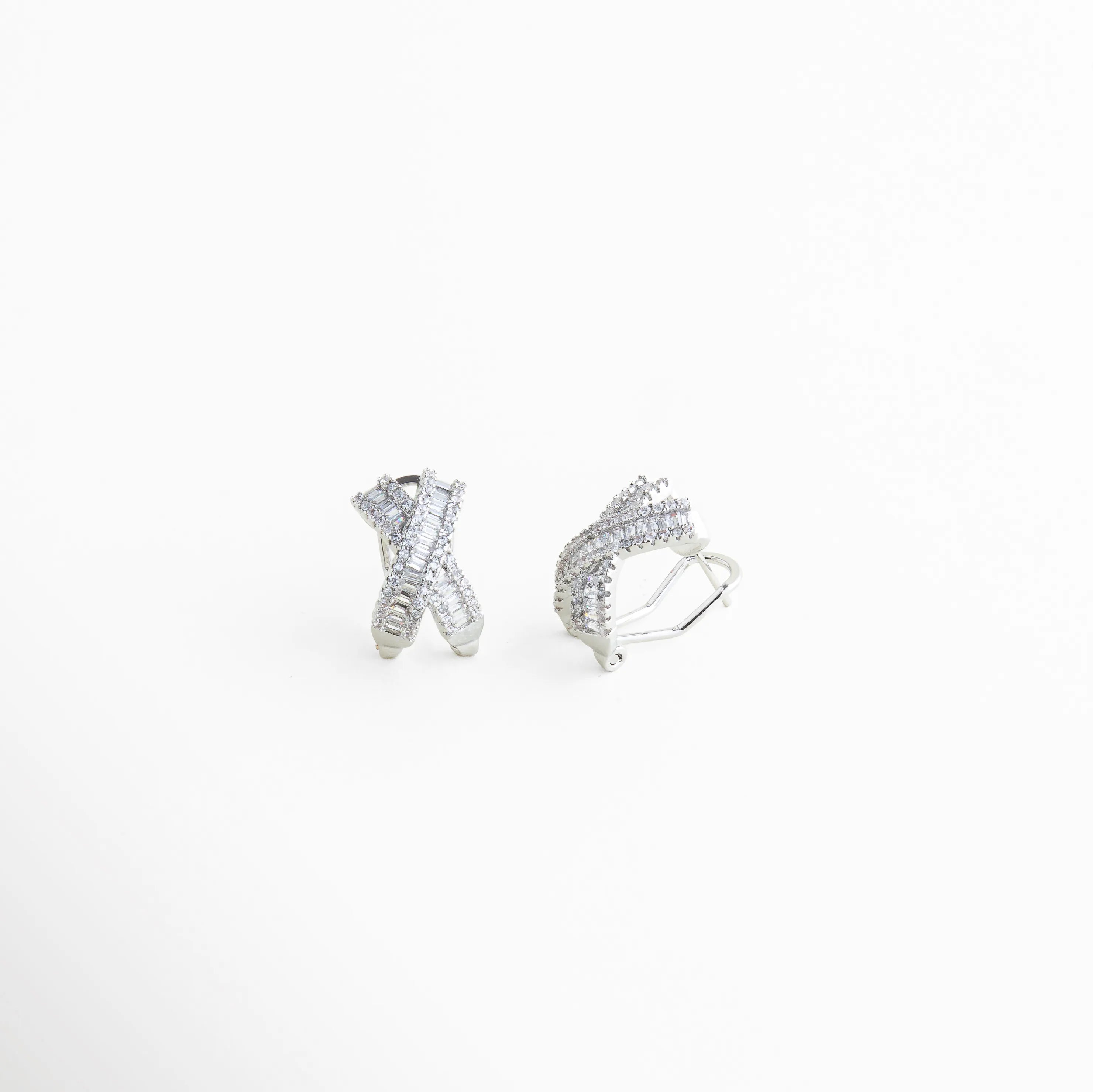 aretes plateados cruzados vistos en ángulo, detalle de zirconias en aretes tipo X, aretes elegantes con textura y brillo, diseño cruzado moderno en aretes pequeños, aretes plateados con acabado pulido, joyería contemporánea aretes stud con piedras