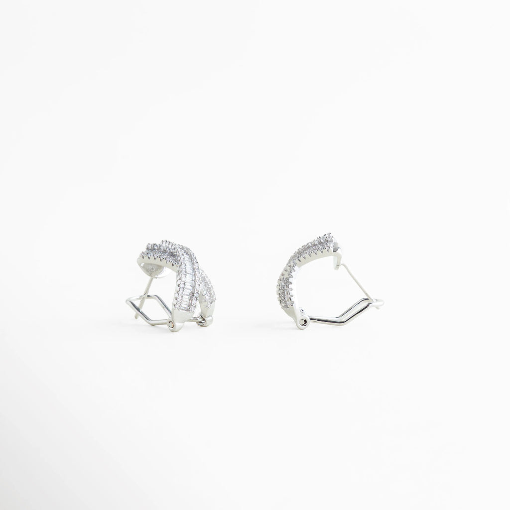 aretes plateados con broche tipo poste, cierre posterior de aretes tipo stud, aretes cruzados con estructura sólida, detalle lateral de aretes con zirconias, aretes pequeños cómodos para uso diario, broche metálico resistente en aretes elegantes