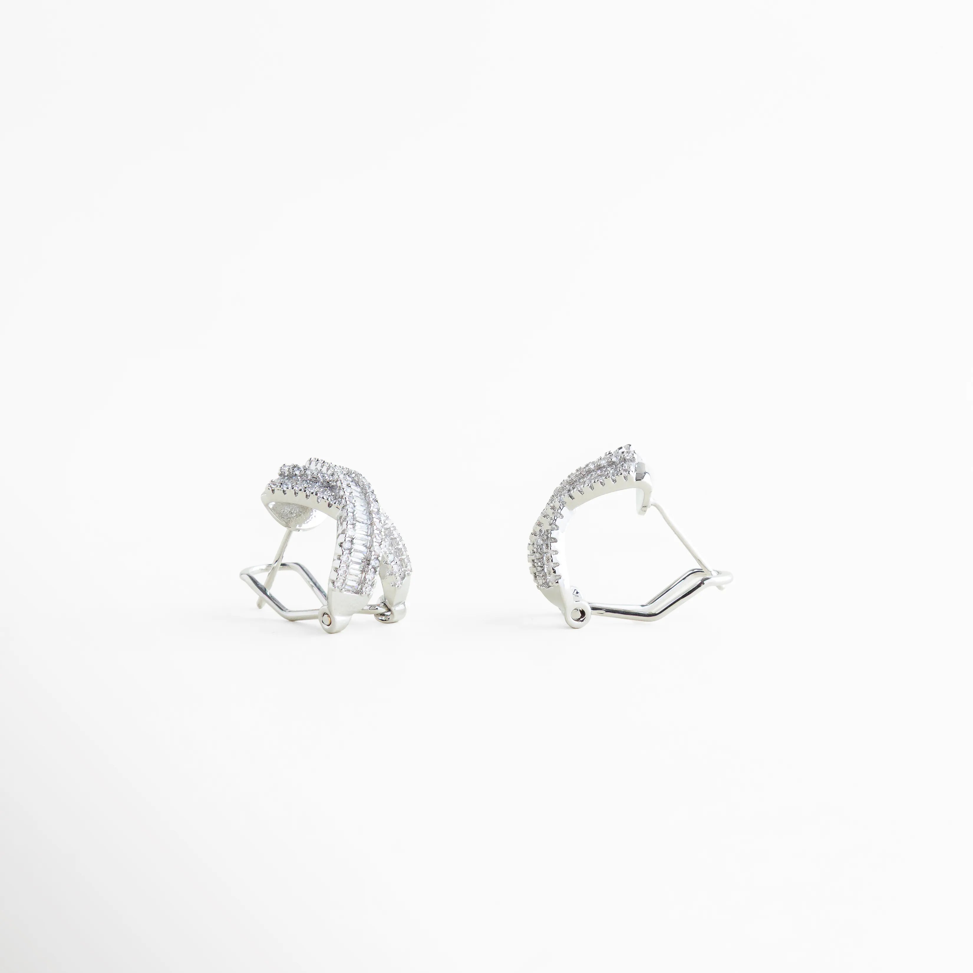 aretes plateados con broche tipo poste, cierre posterior de aretes tipo stud, aretes cruzados con estructura sólida, detalle lateral de aretes con zirconias, aretes pequeños cómodos para uso diario, broche metálico resistente en aretes elegantes