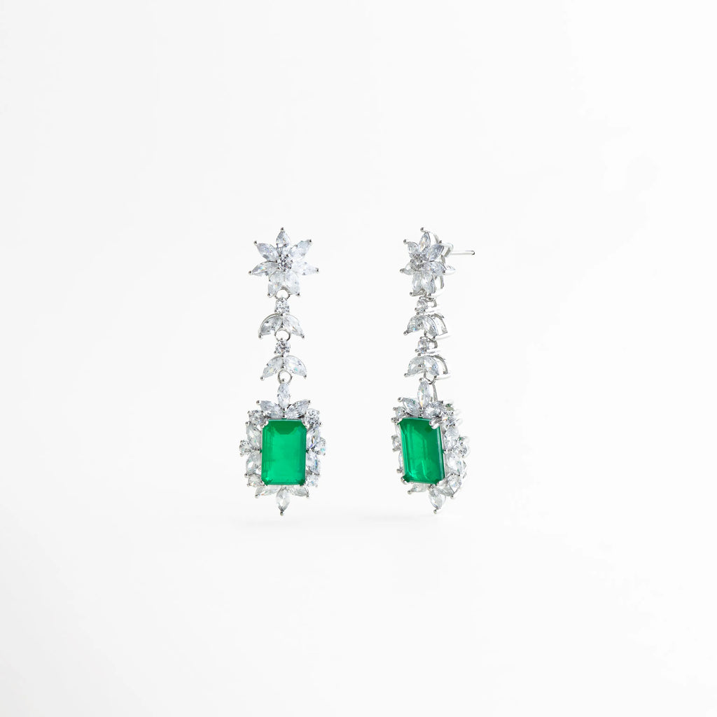 detalle de piedra verde central con marco de circonias plateadas, acercamiento a circonias brillantes en aretes largos plateados, detalle del corte rectangular de la piedra verde en aretes elegantes, textura brillante y pulido fino en aretes con piedra verde, composición delicada de circonias en aretes largos de diseño vertical