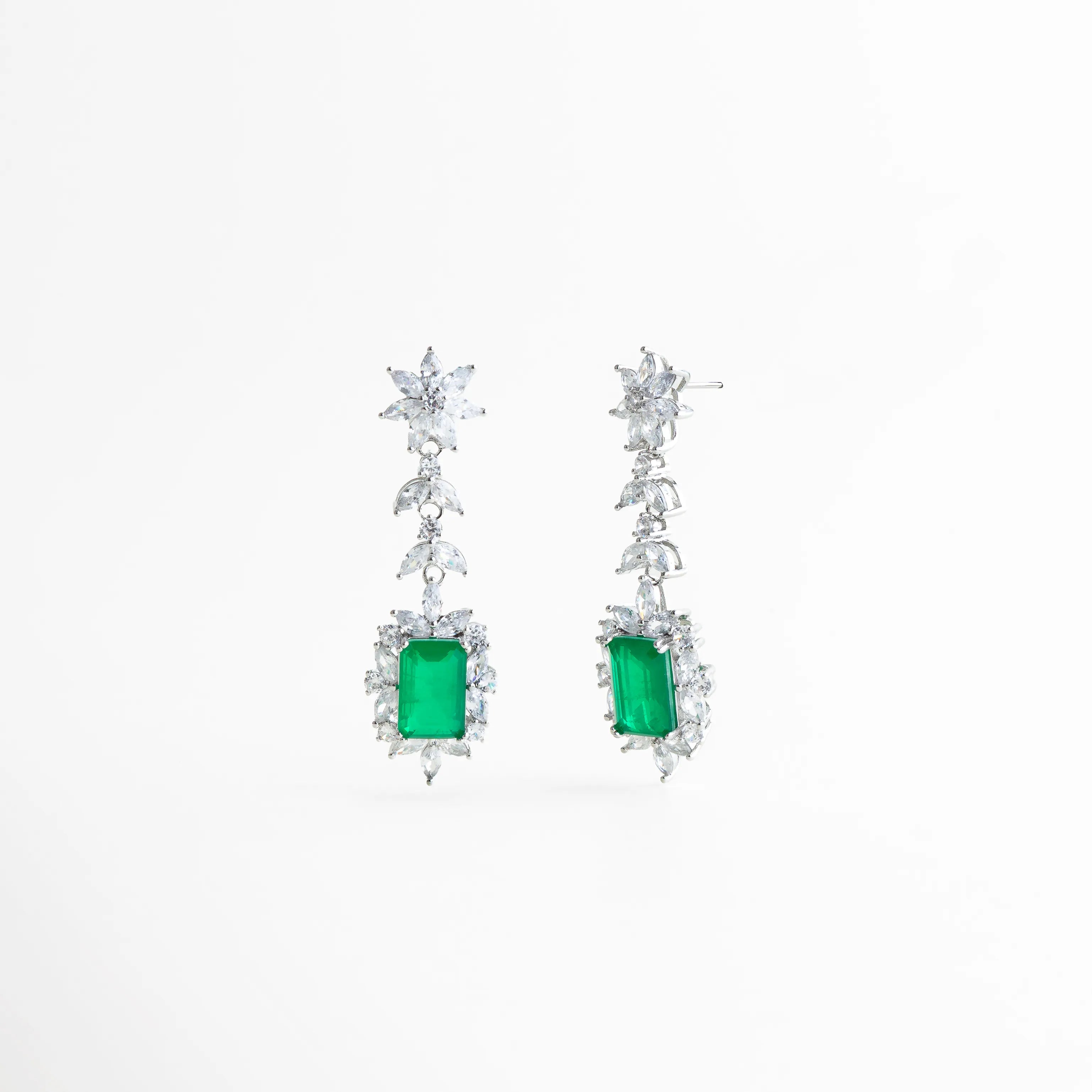 detalle de piedra verde central con marco de circonias plateadas, acercamiento a circonias brillantes en aretes largos plateados, detalle del corte rectangular de la piedra verde en aretes elegantes, textura brillante y pulido fino en aretes con piedra verde, composición delicada de circonias en aretes largos de diseño vertical