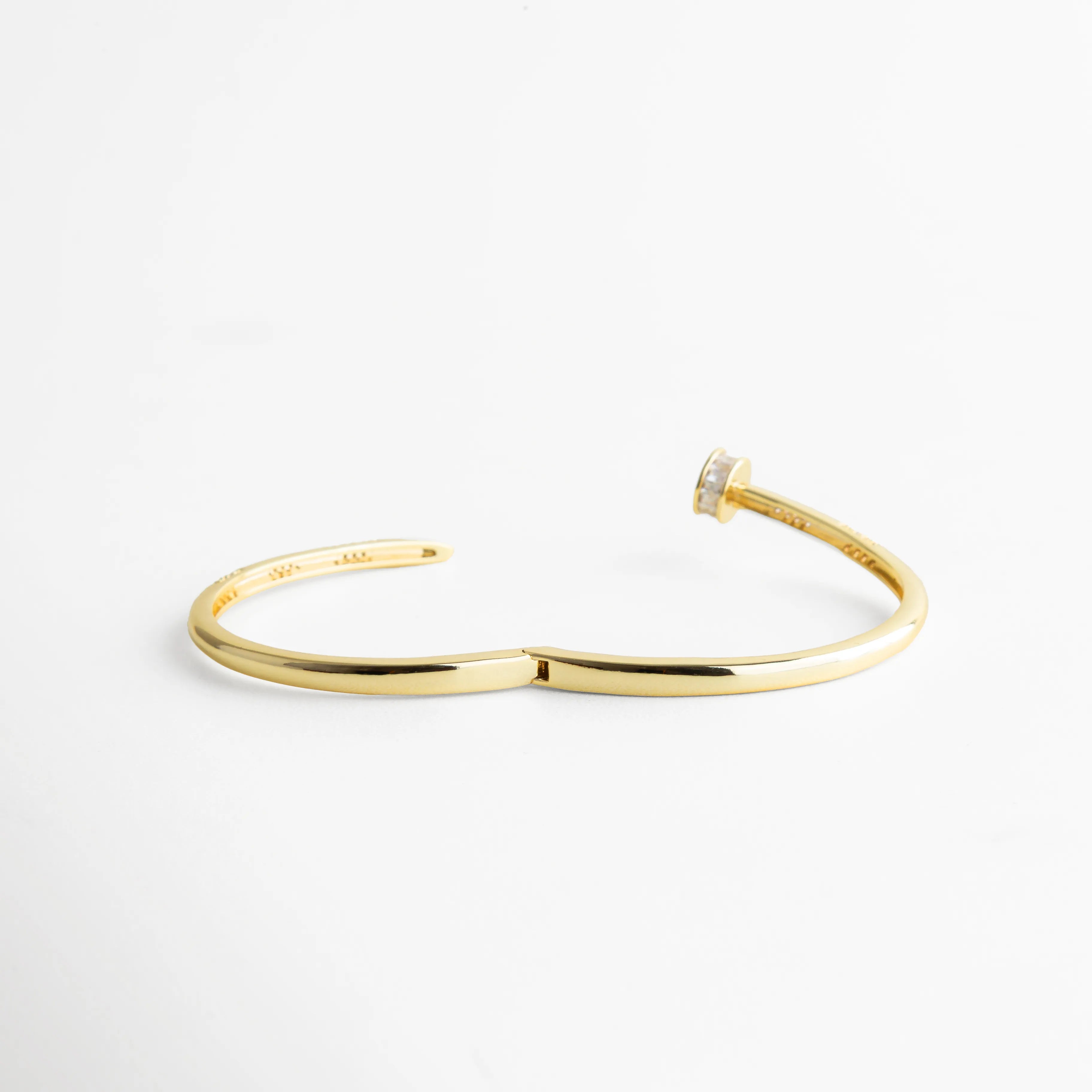 pulsera dorada completamente abierta mostrando su flexibilidad y estructura delgada, fotografiada sobre fondo blanco