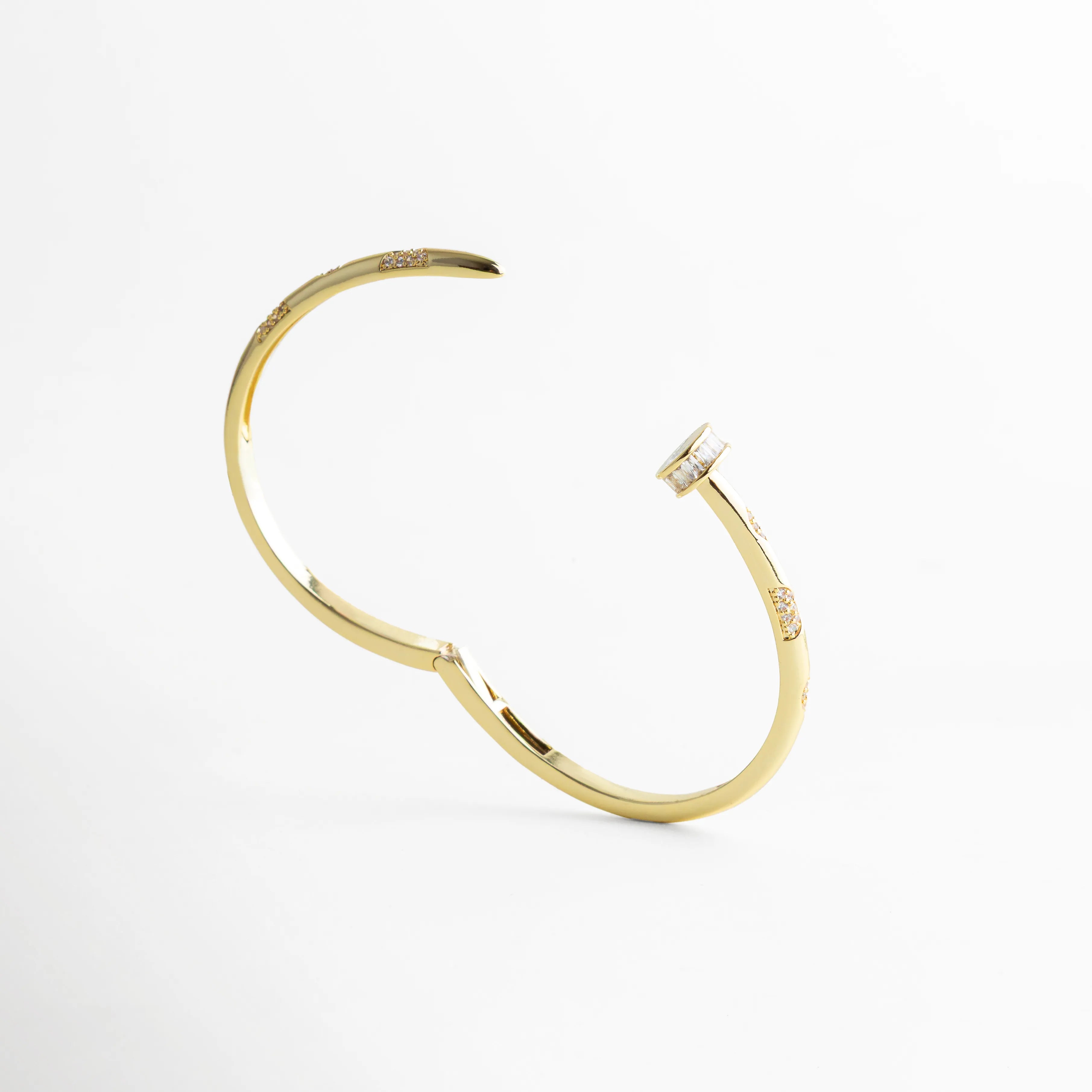 pulsera dorada semi abierta flotando ligeramente, mostrando los detalles laterales con zirconias, sobre fondo blanco limpio