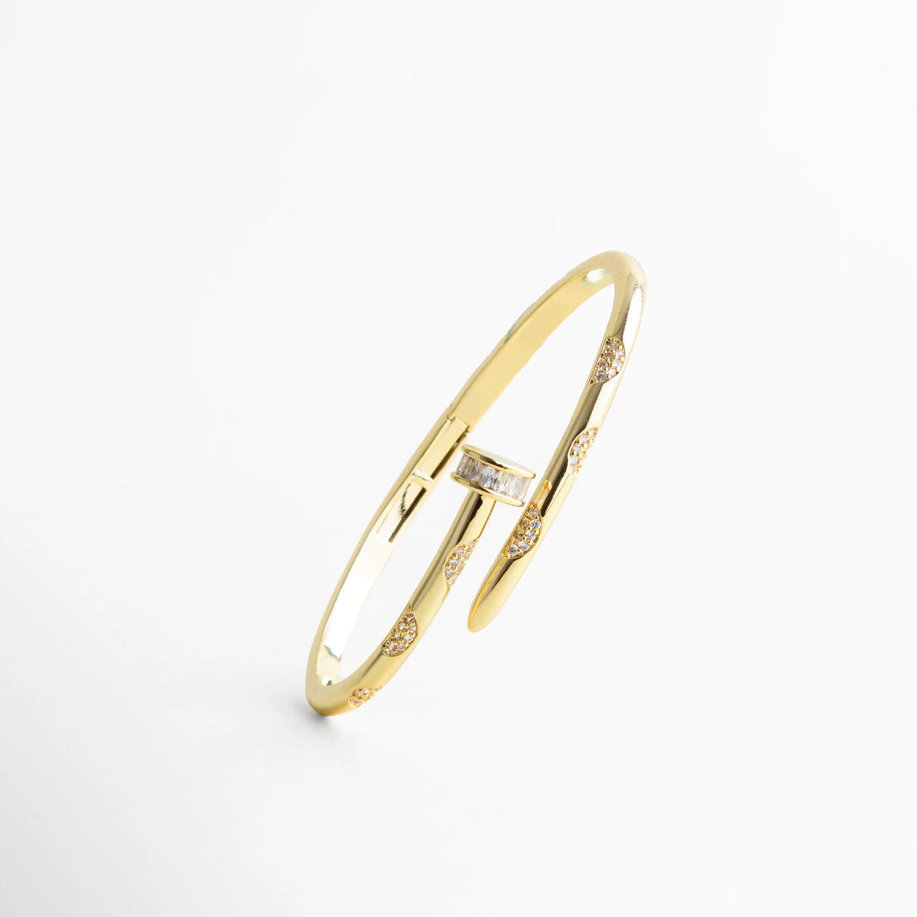 pulsera dorada vista inclinada con perspectiva diagonal, destacando el diseño de clavo y la pieza frontal rectangular con zirconias