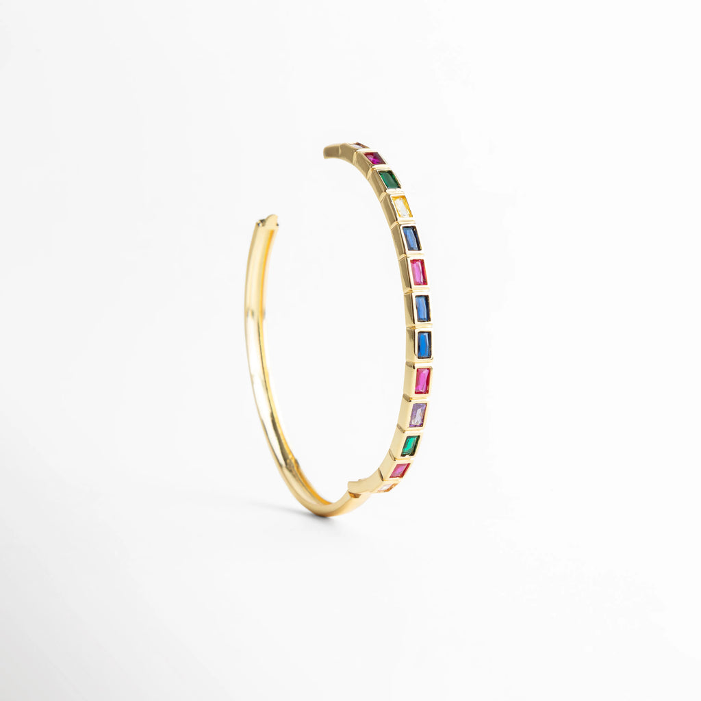 Pulsera dorada en forma curva con zirconias multicolor, Vista curva de pulsera con piedras de colores brillantes, Pulsera Jolie en ángulo con diseño delicado y vibrante, Curvatura de pulsera con zirconias multicolor y brillo elegante, Pulsera con forma circular parcial y detalles de colores