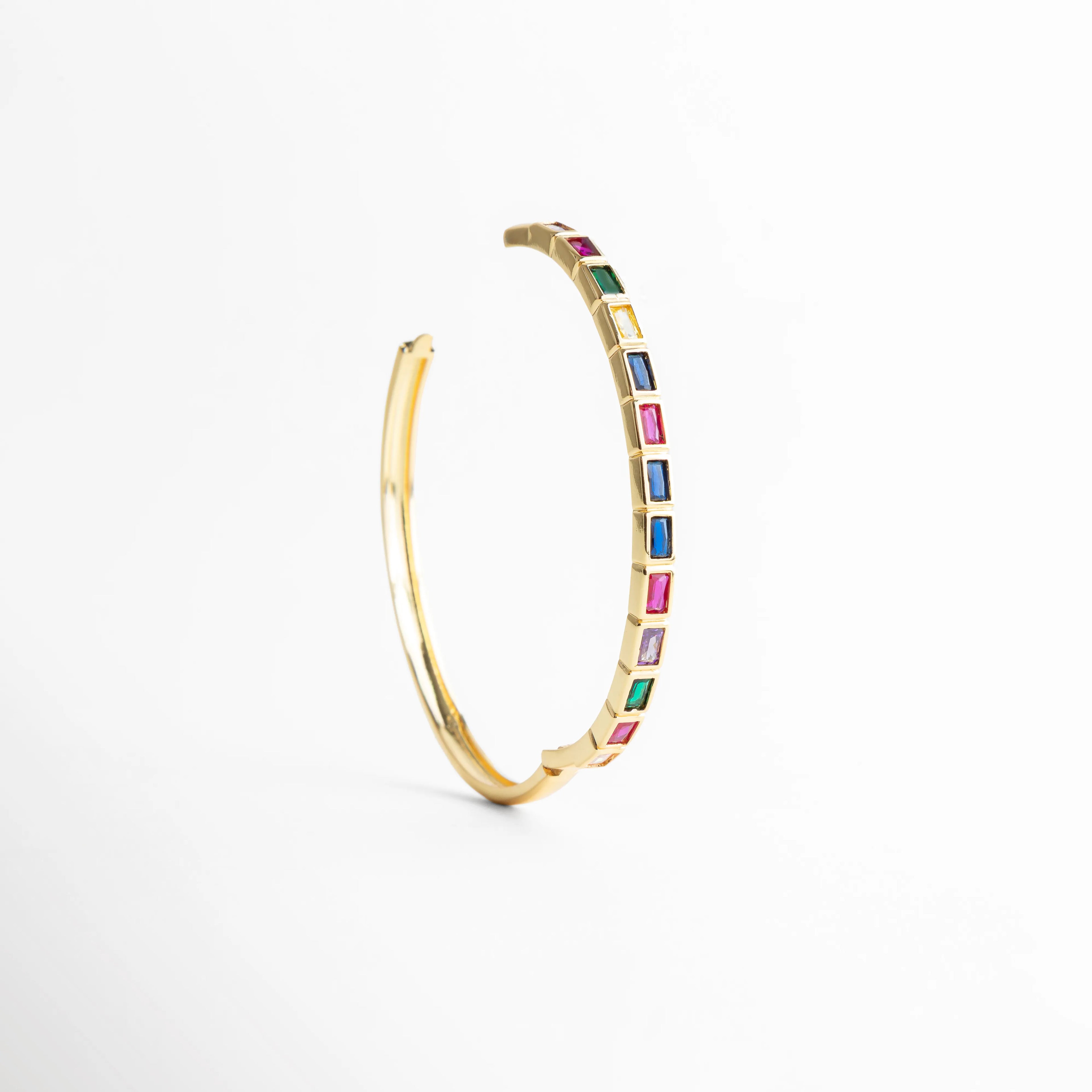 Pulsera dorada en forma curva con zirconias multicolor, Vista curva de pulsera con piedras de colores brillantes, Pulsera Jolie en ángulo con diseño delicado y vibrante, Curvatura de pulsera con zirconias multicolor y brillo elegante, Pulsera con forma circular parcial y detalles de colores