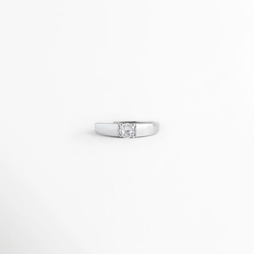 Anillo solitario ajustable enchapado en oro blanco con banda lisa y piedra circonia cuadrada en el centro, vista frontal sobre fondo blanco, Vista de frente de anillo minimalista en tono plata con una sola circonia central de corte cuadrado o princesa, Anillo ajustable de bisutería fina de 0.5 cm con acabado brillante y gema transparente incrustada, Detalle frontal de anillo delgado plateado con engaste plano de circonia cristalina central.