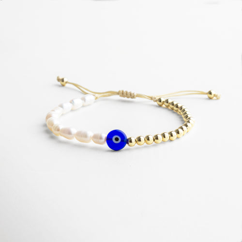 Primer plano del dije de ojo turco en tonos azul y blanco con incrustaciones de perlas naturales de agua dulce, montado sobre chapa de oro 18K con acabado brillante y duradero