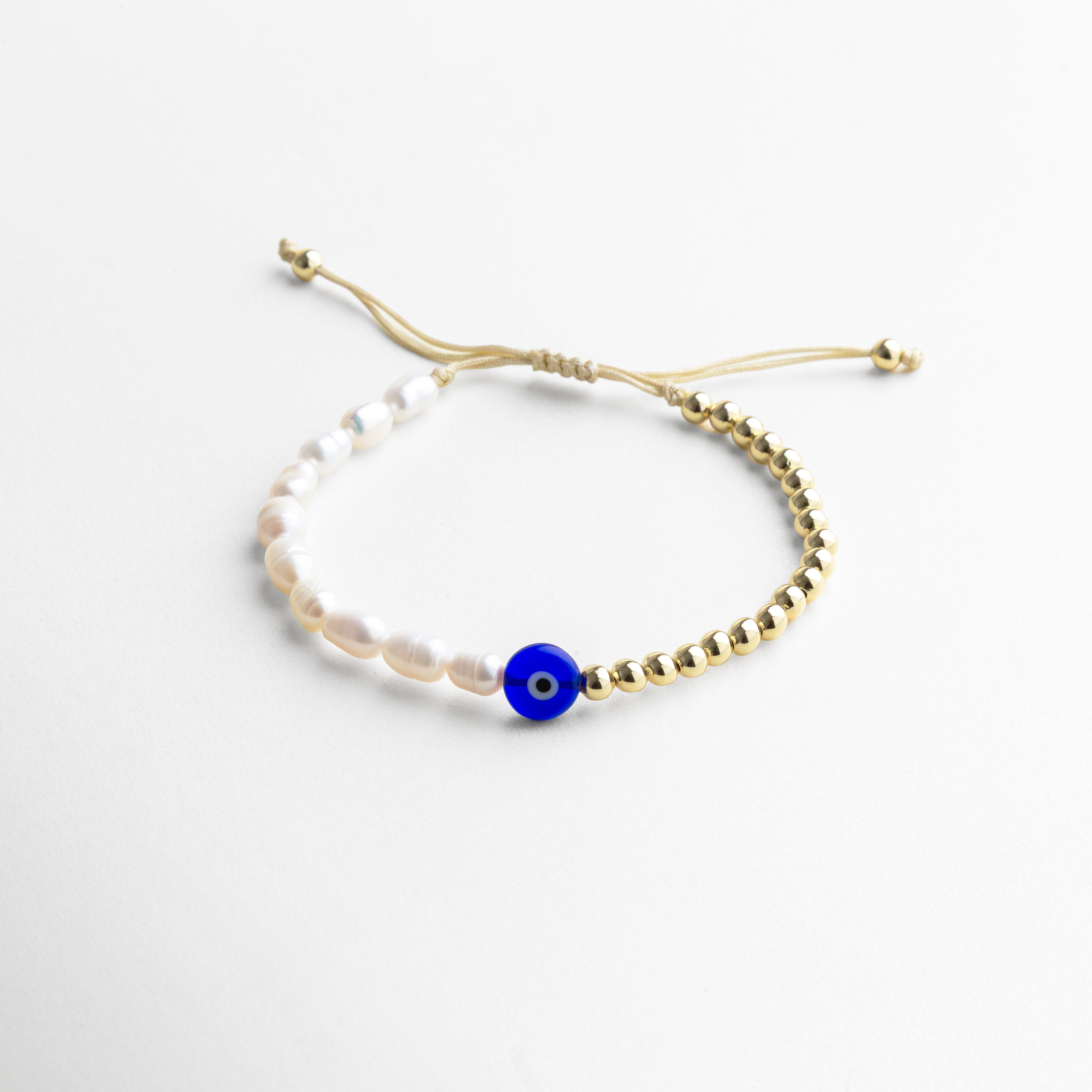 Pulsera dorado ajustable con dije central de ojo turco rodeado de perlas de agua dulce, diseñado como amuleto de protección y buena suerte, ideal para uso diario o como regalo significativo