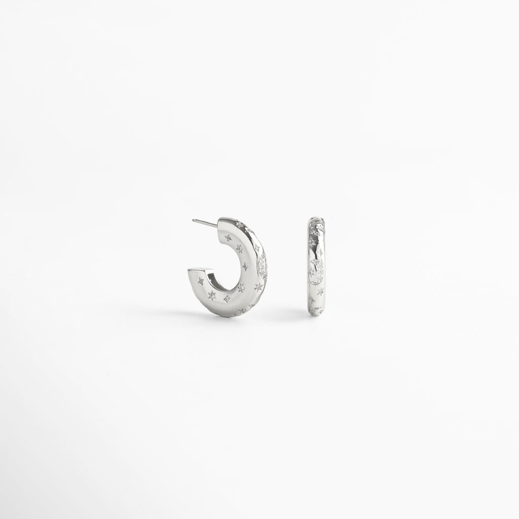 Aretes de aro en cobre con recubrimiento enchapado en oro blanco 18K, superficie pulida con incrustaciones de diamantes de imitación y pequeñas estrellas grabadas, diseño contemporáneo que mezcla estilo moderno y elegancia atemporal.