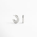 Aretes de aro en cobre con recubrimiento enchapado en oro blanco 18K, superficie pulida con incrustaciones de diamantes de imitación y pequeñas estrellas grabadas, diseño contemporáneo que mezcla estilo moderno y elegancia atemporal.