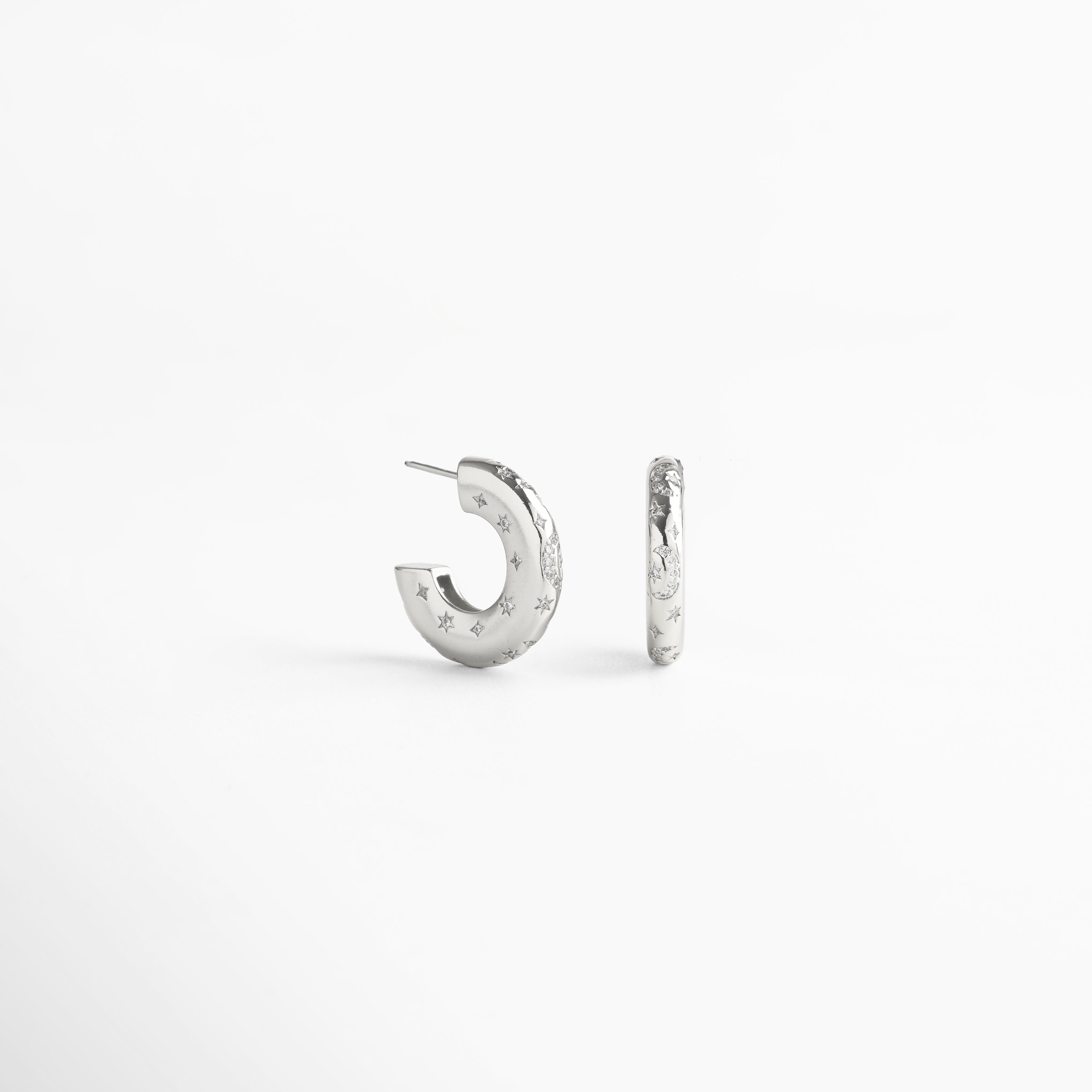 Aretes de aro en cobre con recubrimiento enchapado en oro blanco 18K, superficie pulida con incrustaciones de diamantes de imitación y pequeñas estrellas grabadas, diseño contemporáneo que mezcla estilo moderno y elegancia atemporal.