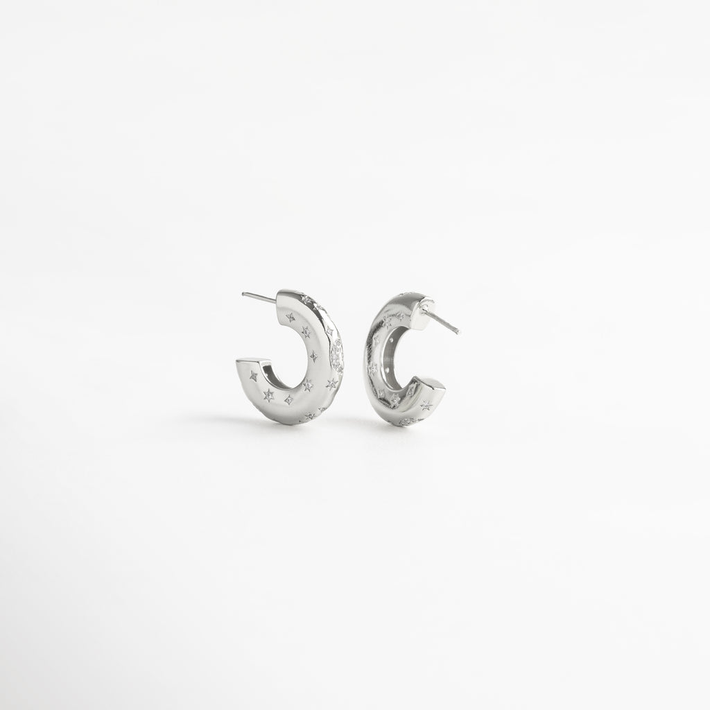 Aretes de aro en cobre con recubrimiento en oro blanco 18K e incrustaciones de diamantes de imitación, diseño grueso de 2 cm de largo y 0.5 cm de ancho con grabado de estrellas, joya moderna y elegante que simboliza fuerza y confianza.