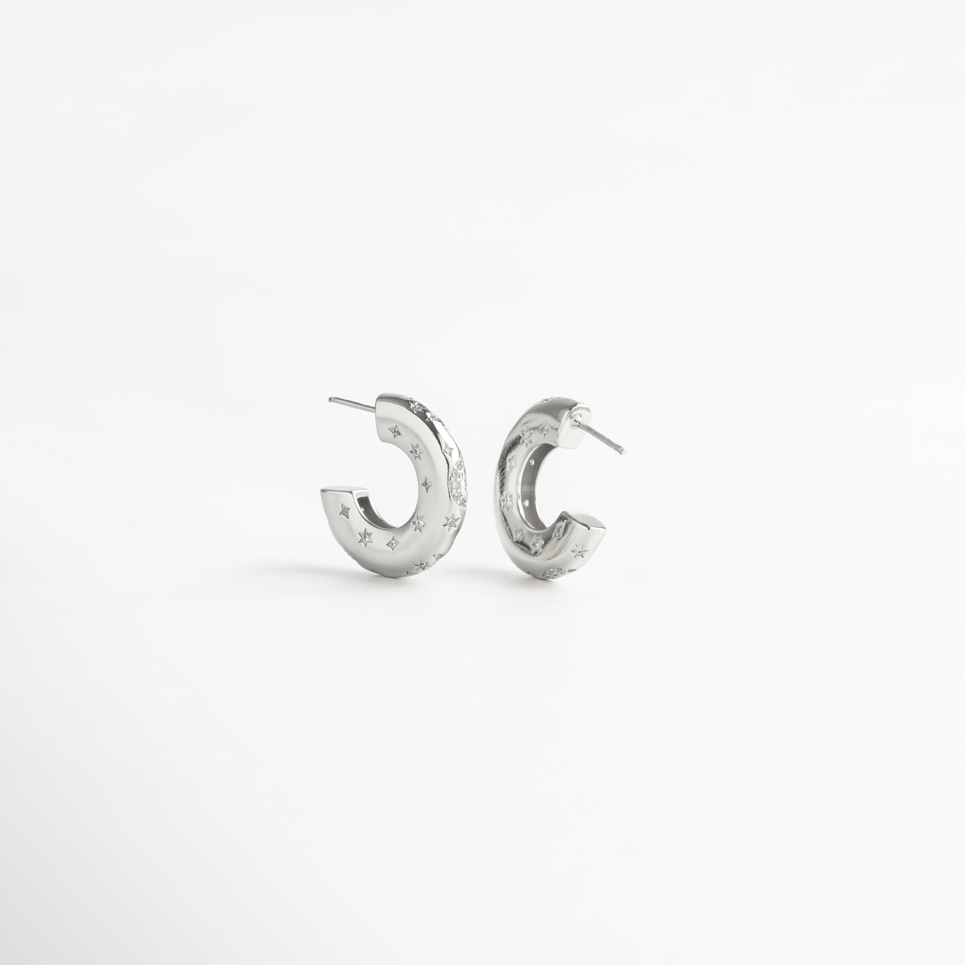 Aretes de aro en cobre con recubrimiento en oro blanco 18K e incrustaciones de diamantes de imitación, diseño grueso de 2 cm de largo y 0.5 cm de ancho con grabado de estrellas, joya moderna y elegante que simboliza fuerza y confianza.