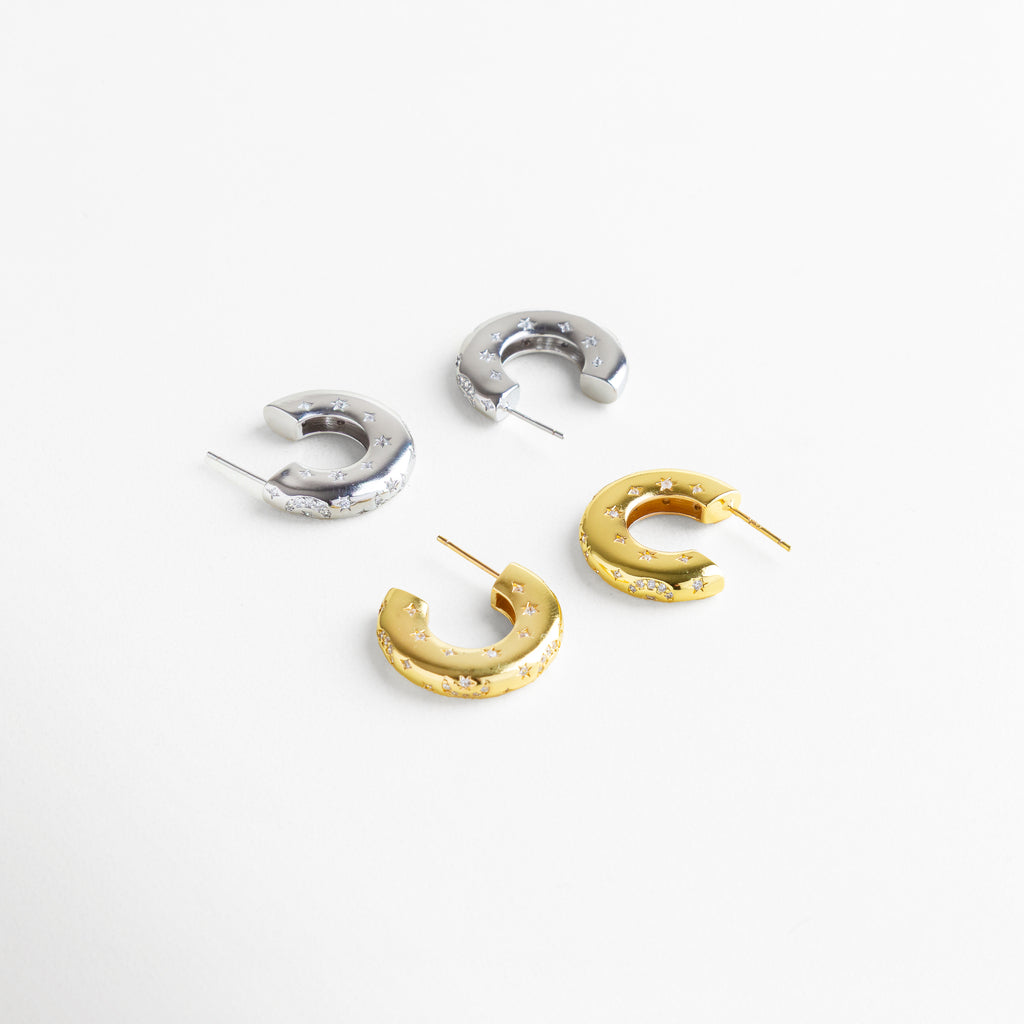 Aretes de aro de cobre con recubrimiento en oro 18K y oro blanco 18K, diseño grueso con grabados de estrellas e incrustaciones de diamantes de imitación, imagen mostrando ambas versiones metálicas como opción versátil y sofisticada.