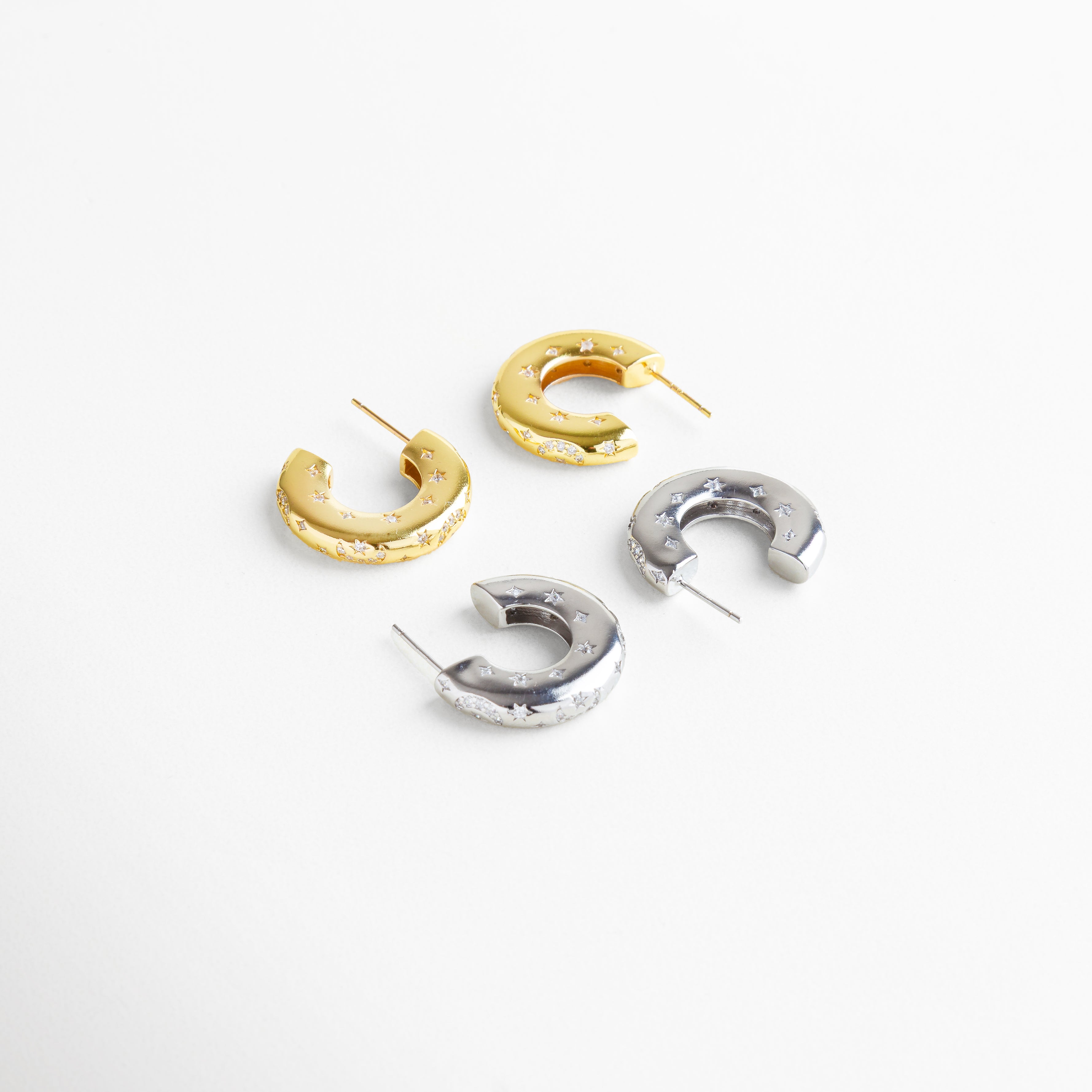 Aretes de aro de cobre con recubrimiento en oro blanco 18K y oro 18K, diseño grueso con grabados de estrellas e incrustaciones de diamantes de imitación, imagen mostrando ambas versiones metálicas como opción versátil y sofisticada.