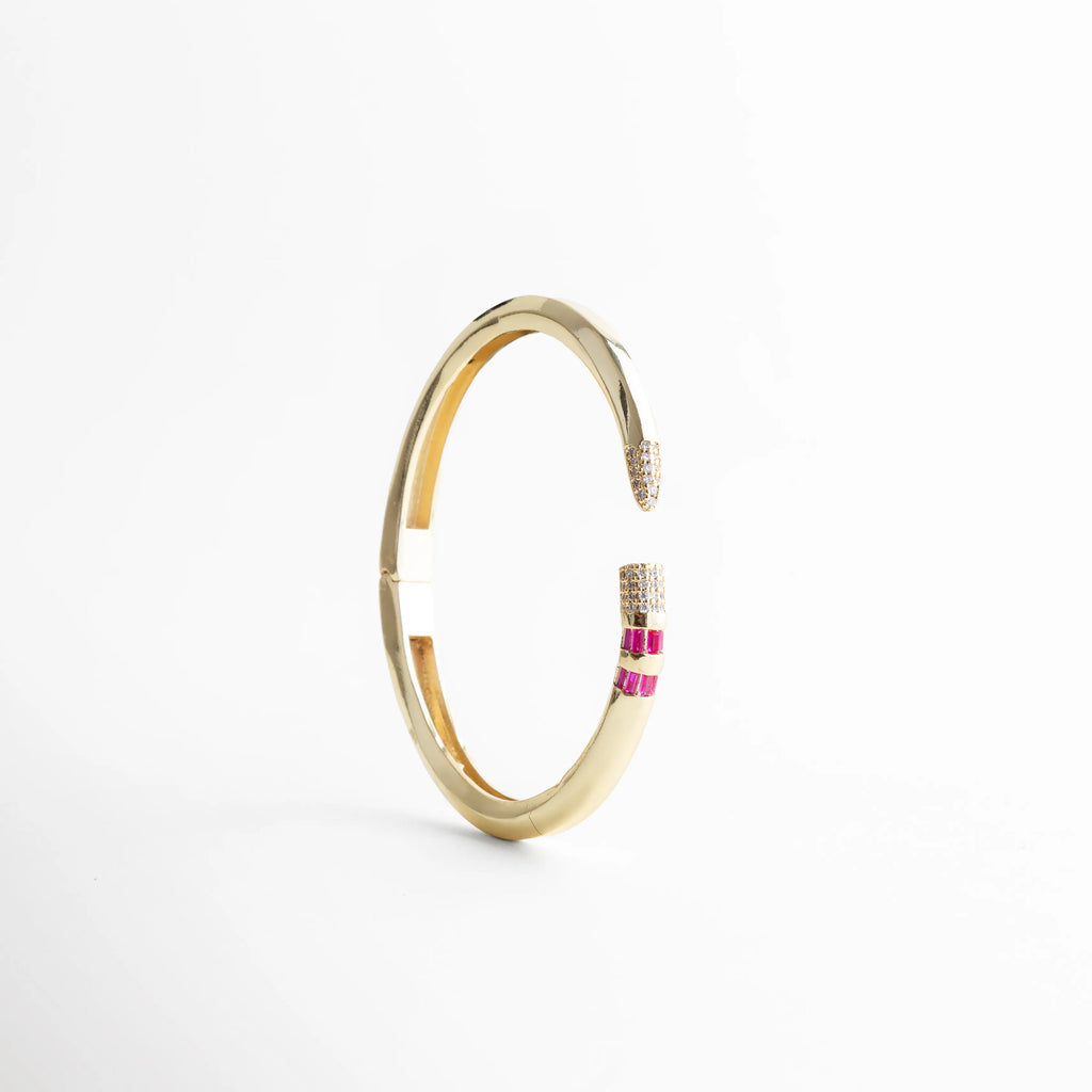 Vista lateral del brazalete circular dorado resaltando su estructura rígida y ergonómica, Pulsera de oro 18K con diámetro de 6.5 cm y diseño moderno de puntas encontradas, Brazalete con bisagra invisible que muestra la curvatura perfecta y el brillo del acabado, Accesorio de muñeca dorado con piedras brillantes, vista vertical de perfil delgado, Brazalete de cobre enchapado en oro con detalle de micro-pavé en los extremos.