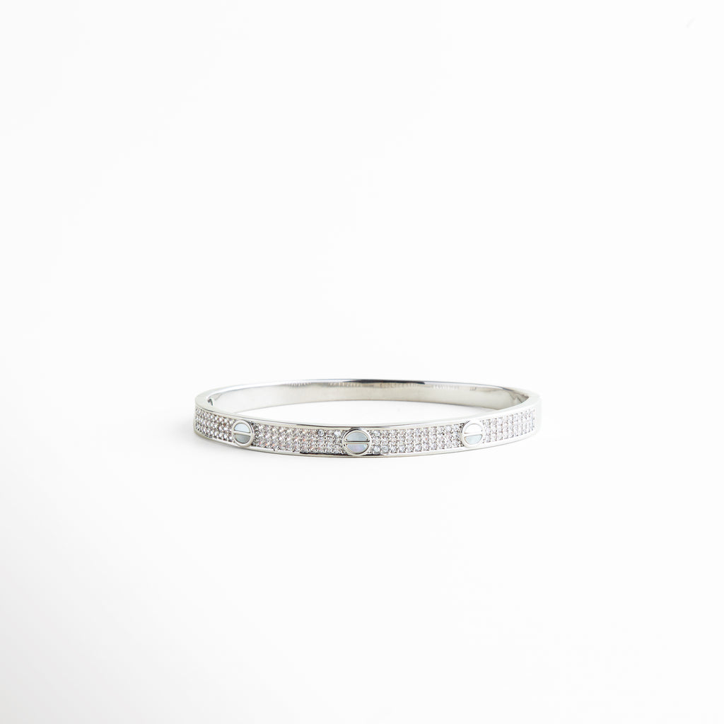 pulsera delgada plateada con detalles circulares grabados, pulsera minimalista de metal con acabado pulido, pulsera femenina estilo moderno vista frontal, joyería minimal pulsera rígida con diseño geométrico, pulsera elegante delgada para uso diario