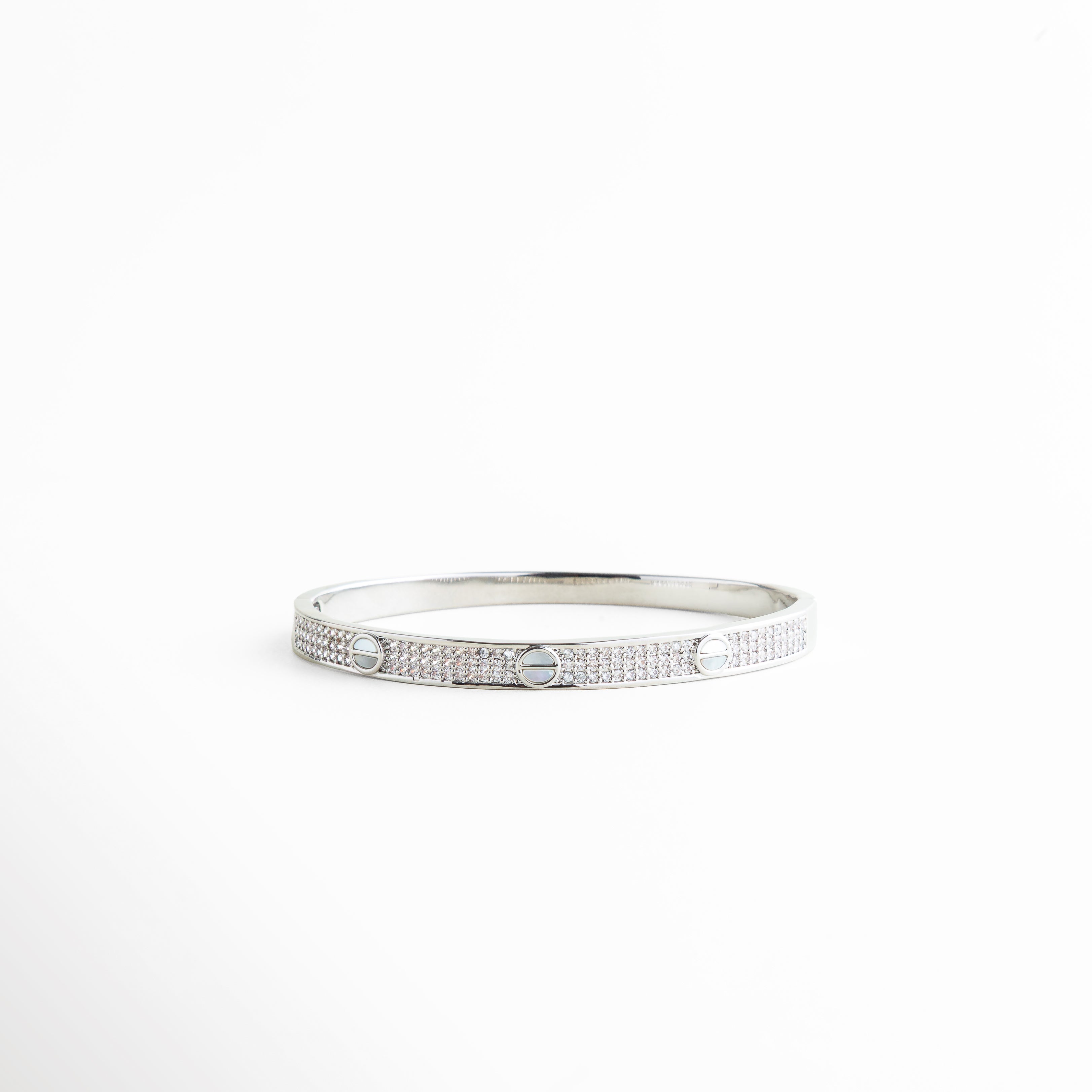 pulsera delgada plateada con detalles circulares grabados, pulsera minimalista de metal con acabado pulido, pulsera femenina estilo moderno vista frontal, joyería minimal pulsera rígida con diseño geométrico, pulsera elegante delgada para uso diario