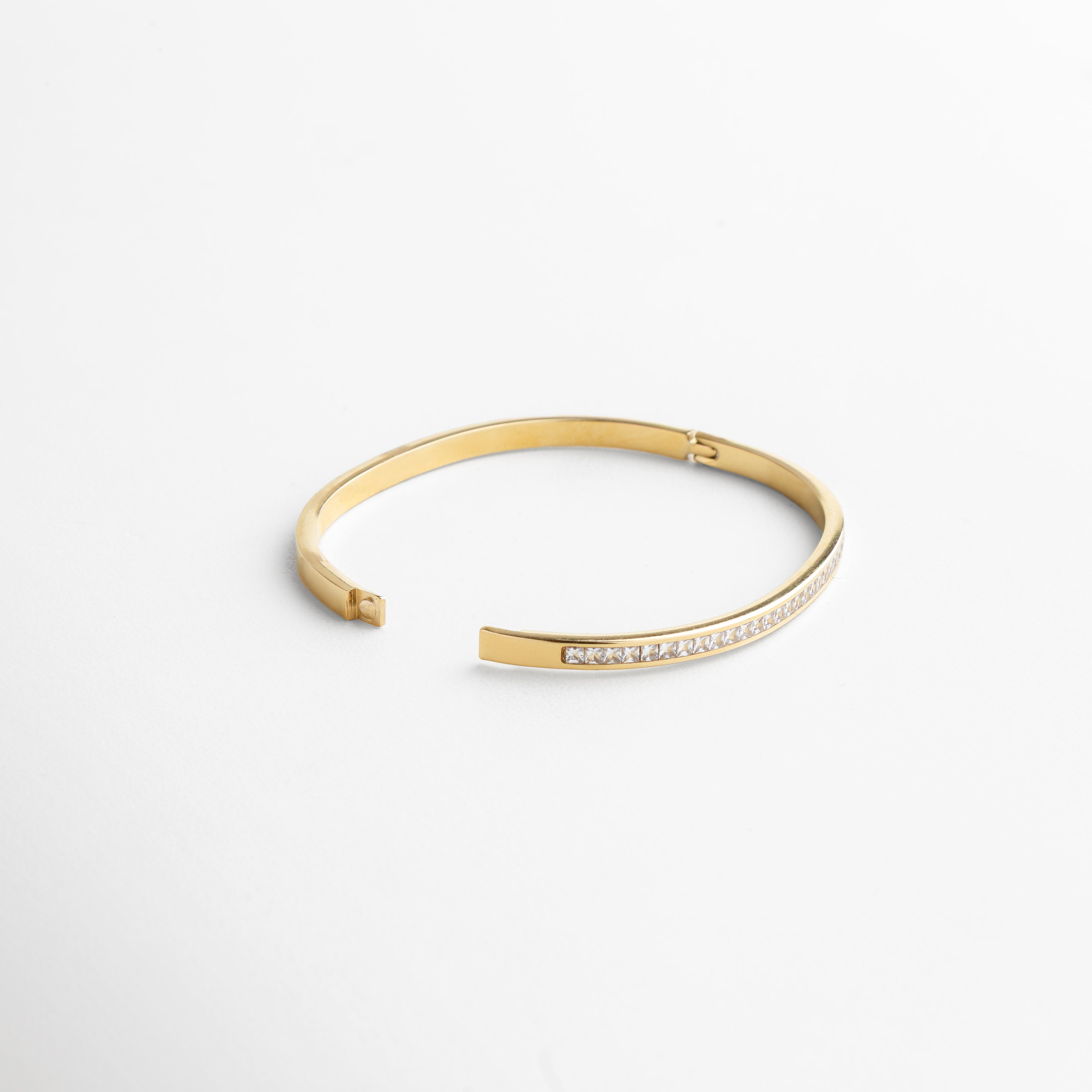 perfil lateral del brazalete mostrando su estructura delgada, diseño fino de 0.4 cm de ancho, silueta ligera que aporta comodidad, proporción elegante entre metal y piedras, estética minimalista y chic