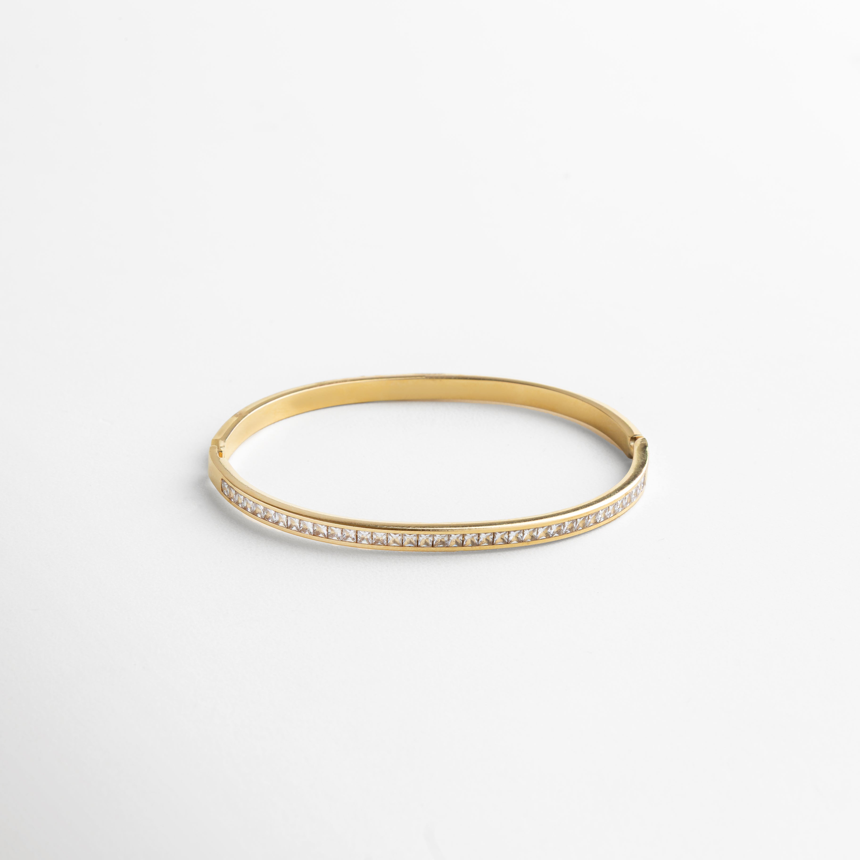pulsera dorada tipo brazalete con incrustaciones de zirconias diamante, diseño minimalista y refinado, acabado en oro 18K que aporta brillo cálido, pieza versátil para looks elegantes o casuales, joya que deslumbra con sutileza
