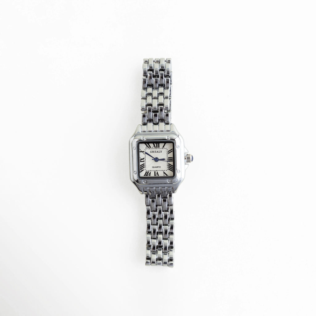 Reloj de mujer con carátula cuadrada y acabado en oro blanco, diseño elegante y sofisticado, Vista frontal de reloj femenino en acero inoxidable con estilo refinado y brillo sutil, Reloj elegante para mujer con carátula pequeña y acabado brillante en oro blanco, Carátula de reloj femenino con diseño moderno y acabado en acero inoxidable en tono plata, Reloj de mujer sofisticado con acabado en oro blanco y estilo delicado para uso diario.