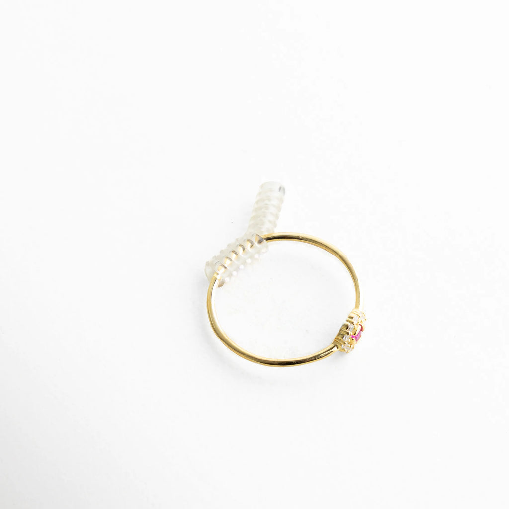 Anillo dorado con detalle floral al frente y resorte flexible en la parte trasera, ideal para ejemplificar su funcionalidad. El contraste entre la textura suave del silicón y el brillo del metal añade una sensación de confort y durabilidad.