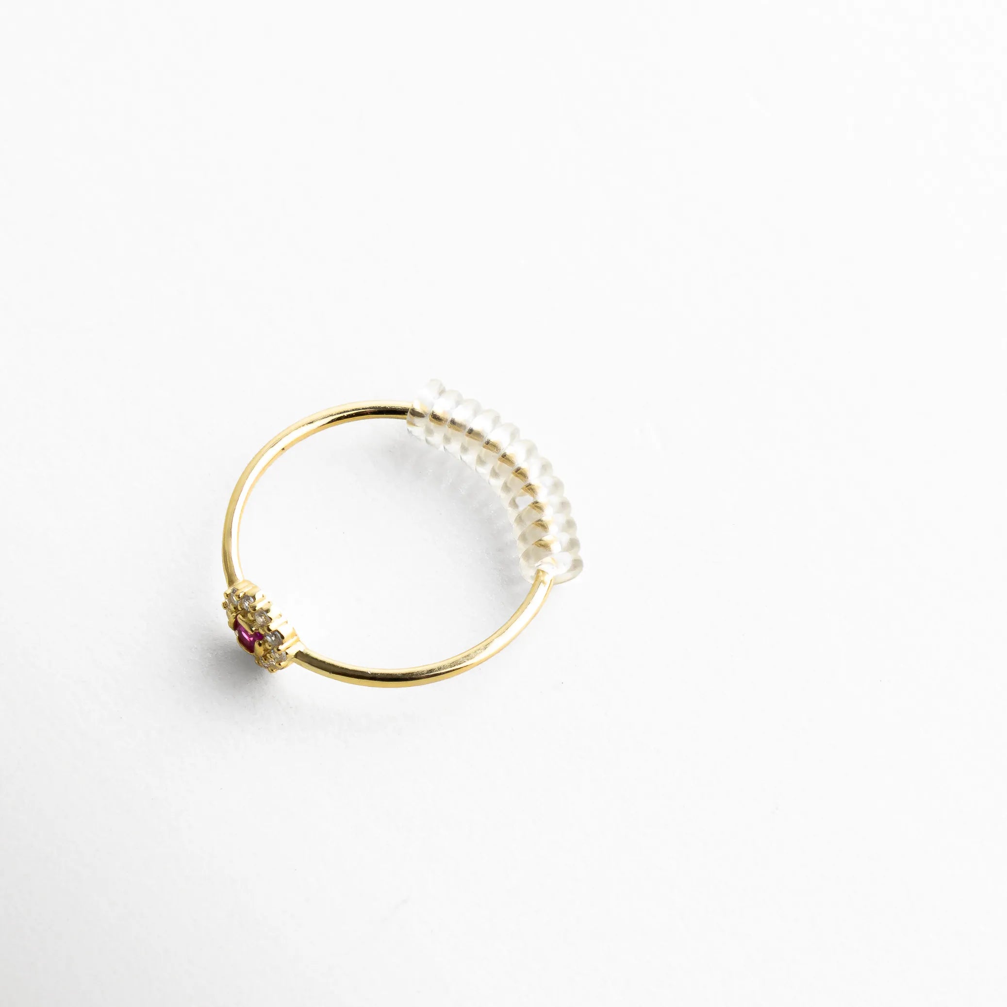 Anillo fino en tono dorado con resorte de silicón transparente, diseñado para brindar ajuste perfecto sin alterar la estética de la joya. La toma permite apreciar cómo el accesorio se integra de manera casi invisible, manteniendo la delicadeza del diseño original.