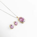 Vista inclinada del Set Loisa con collar y aretes de zirconia rosa, Set de joyería dorada con aretes y collar de piedra rosada brillante, Conjunto elegante de collar y aretes con zirconia ovalada en tono rosa, Set femenino de bisutería fina con acabado dorado y brillo sofisticado, Set Loisa con diseño delicado y elegante para complementar cualquier look.
